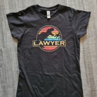 Black tshirt lying on a grey background with the word LAWYER under a silhouette of a Tyrannosaur