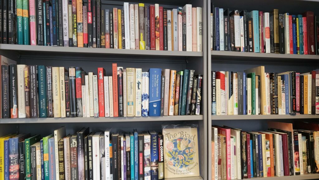 Three levels of a book shelf containing books about Art Crime