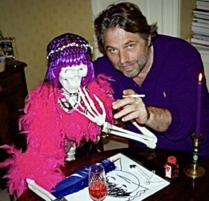 A man in his 40s or 50s is pictured holding a cigarette with his arm around a life size model skeleton that is wearing a feather boa and a wig. The man is Michel van Rijn.